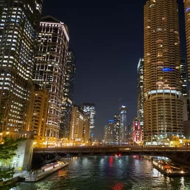 The river at night between lit towers, a bridge glowing across it