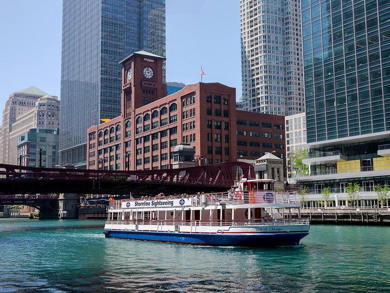 A sightseeing boat on the river below a brick clock tower