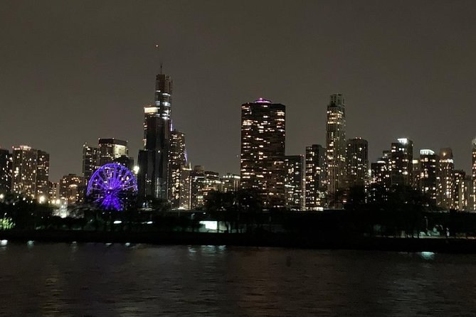 The skyline at night from the lake, a lit Ferris wheel on the pier